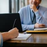 Crop anonymous female filling questionnaire when applying for job sitting in employer office